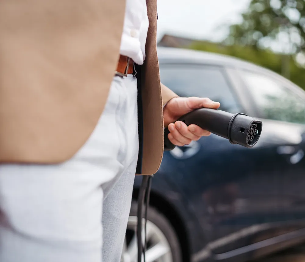 Driver plugging a VOLT Charge connector into an electric car